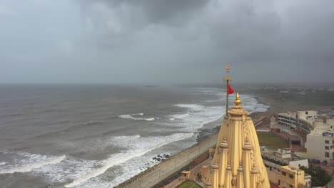 Aerial-rotating-shot-of-saffron-flag-blowing-in-the-top-of-Somnath-mandir-during-cloudy-weather-