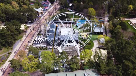 Construction-process-of-Ferris-wheel-in-Palanga-downtown,-aerial-ascend-view