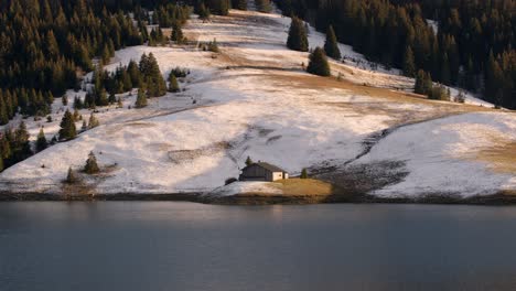 Beautiful-shot-of-a-lonely-farm-in-front-of-a-lake-in-the-mountains