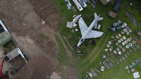 Top-down-aerial-view-above-hawker-hunter-jet-renovation-surrounded-by-parts-on-Gloucestershire-farmland