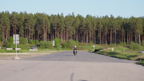 Motorbike-rider-with-helmet-on-road-in-the-forest-approaching-the-camera