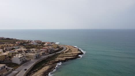 Drone-Vuela-A-Un-Punto-De-Descanso-Para-Surfear-En-Sicilia-En-Italia,-Autos-Conduciendo-En-La-Carretera-De-La-Costa