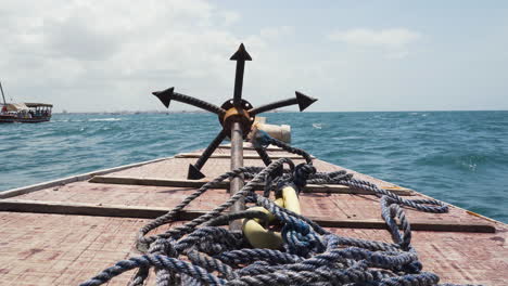 Iron-grappling-anchor-and-rope-on-bow-deck-of-sailing-wooden-boat