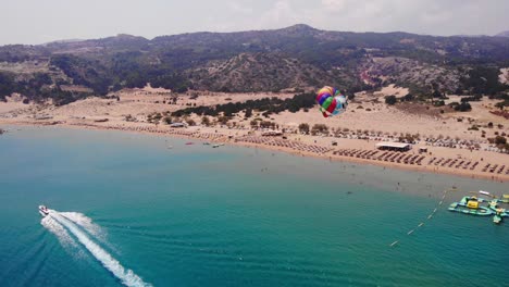 Touristisches-Parasailing-Mit-Buntem-Fallschirm,-Der-An-Einem-Sommertag-Auf-Der-Insel-Rhodos,-Griechenland,-Mit-Dem-Schnellboot-Im-Meer-Gezogen-Wird
