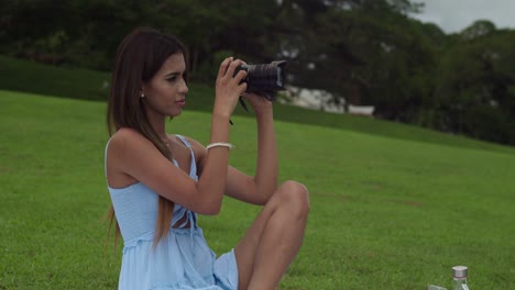 Hispanic-girl-taking-a-photograph-while-holding-a-camera-in-a-tropical-park