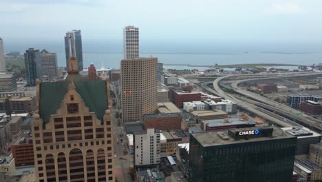 Aerial-view-overlooking-high-rise-in-downtown-Milwaukee,-cloudy,-USA---pan,-drone-shot