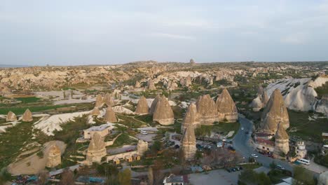 Aerial-forwarding-shot-of-beautiful-fairy-chimneys-along-with-residential-houses-in-Cappadocia,-Turkey-during-evening-time