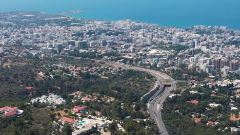 Fliegen-über-Eine-Autobahn-Mit-Blick-über-Die-Weitläufige-Stadt-In-Richtung-Mittelmeer