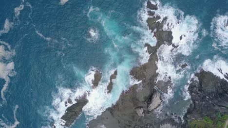Luftaufnahme-Von-Wellen-Des-Indischen-Ozeans,-Die-Felsbrocken-Und-Korallenriffe-Am-Strand-Bei-Sonnigem-Wetter-Treffen---Pengilon-Hill,-Indonesien,-Asien