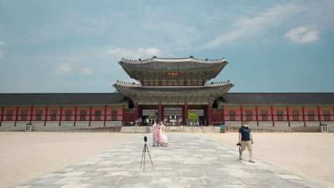 A-Korean-couple-in-hanbok-clothes-and-protective-masks-takes-a-photo-together-with-Heungnyemun-Gate-traveling-at-Gyeongbokgung-Palace