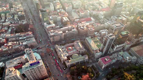 Aerial-dolly-in-of-National-library-and-National-Archive-of-Chile,-traffic-in-avenue-an-Downtown-Santiago-buildings-at-sunset,-Chile