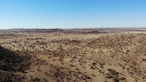 A-panning-drone-shot-that-captures-the-dry,-sandy,-shrubby-terrain-of-a-savanna-landscape