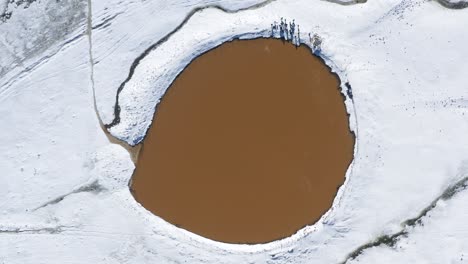 Aerial-top-down-rotation-of-a-crater-lake-Birkat-Ram,-in-snow-on-Mount-Hermon,-Israel,-The-mountain-and-lake-are-in-the-northeastern-Golan-Heights