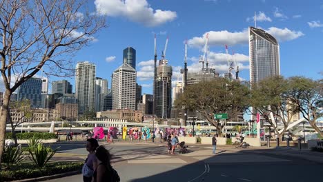 Urban-cityscape-view-of-tourists-visiting-the-iconic-BRISBANE-block-letter-monumental-sign-and-strolling-in-the-sunny-afternoon-at-southbank-with-high-rise-buildings-in-the-background,-QLD-Australia