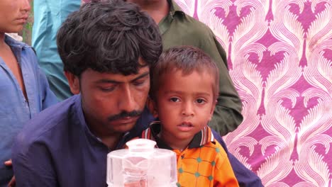Padre-Con-Hijo-Esperando-En-El-Campamento-De-Socorro-De-Inundaciones-En-Sindh,-Pakistán