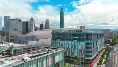 Ascending-aerial-view-of-over-city-of-Taipei,-with-101-Tower,-futuristic-buildings-and-Dome---Beautiful-mountain-range-in-backdrop