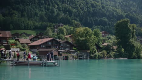 Iseltwald,-Switzerland,-waves,-pole,-pier,-tourists,-crowds,-scenic,-cloudy,-mountain,-lake,-hillside,-summer,-forests,-turquoise,-water,-europe
