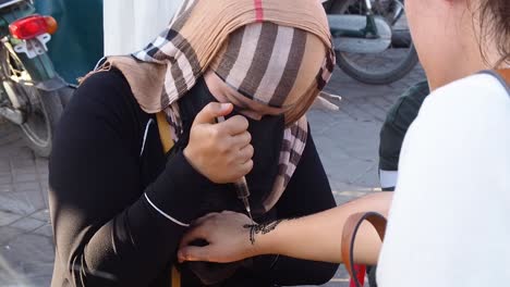 4K-Aufnahmen-Eines-Traditionellen-Henna-Tattoos,-Das-Von-Muslimischen-Frauen-In-Den-Straßen-Von-Marrakesch-Gemacht-Wird