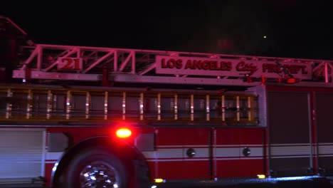 Firetruck-passing-the-camera,-revealing-a-night-fire-scene,-on-the-streets-of-LA,-USA