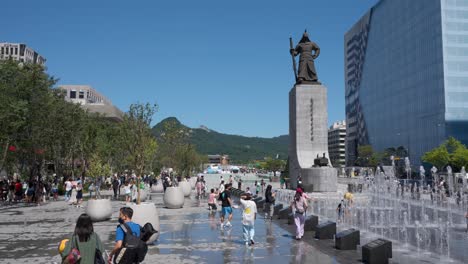 Locals-enjoying-Gwanghwamun-Plaza-around-Yi-Sun-shin-statue-and-fountain,-Seoul