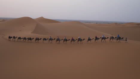 Row-of-camels-with-riders-in-the-Sahara-Desert-at-the-Merzouga-Dunes