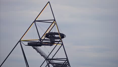 Close-up-shot-of-people-on-Tetraeder-Structure-viewing-platform,-illuminated-at-dusk,-time-lapse
