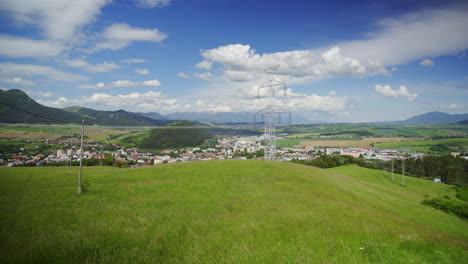 Hierba-Verde-En-El-Prado-Que-Sopla-Con-El-Viento-Con-La-Torre-De-Transmisión-Y-La-Ciudad-De-Ruzomberok-En-La-Distancia-En-Eslovaquia