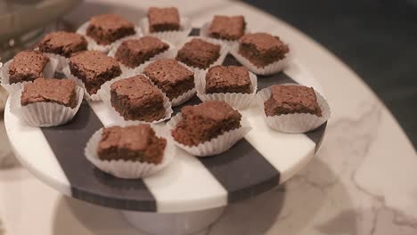 Young-woman-take-of-round-plate-with-baked-brownies,-delicious-chocolates-biscuits,-close-up-shot