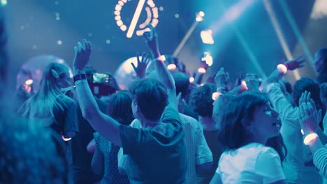 Young-crowd-is-having-a-great-time-at-a-party-waving-their-hands,-slowmotion