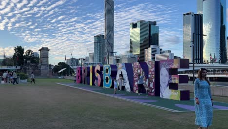 Happy-children-and-adults-having-fun-climbing-up-the-iconic-block-letter-of-Brisbane-city-and-taking-memorable-photos-of-the-landmark-with-downtown-cityscape-as-backdrop,-Queensland,-Australia