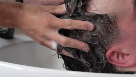 Statische-Zeitlupenaufnahme-Eines-Mannes,-Der-Sich-Die-Haare-Waschen-Lässt