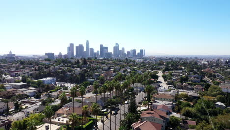 Beautiful-drone-shot-from-a-neighborhood-of-Los-Angeles,-California-showing-palm-trees-and-the-city