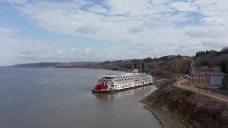 Wide-panning-aerial-shot-of-the-river-cruise-ship-American-Queen-docked-at-the-Port-of-Natchez-in-Mississippi
