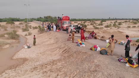 Drone-Captura-La-Vista-Aérea-De-Personas-Que-Están-Distribuyendo-Alimentos-Para-El-Alivio-De-Inundaciones-A-Los-Sobrevivientes-De-Inundaciones-Que-Han-Sido-Desplazados-Y-Afectados-Por-La-Reciente-Inundación-En-Pakistán-Desde-Un-Camión