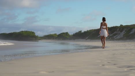 Beautiful-Female-Traveller-Running-Towards-Tortuga-Bay-Beach-With-Waves-Slowly-Breaking-In-The-Galapagos