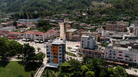 aerial-drone-parks-and-modern-high-rise-office-buildings-in-the-city-Përmet,-municipality-in-Gjirokastër,-Albania