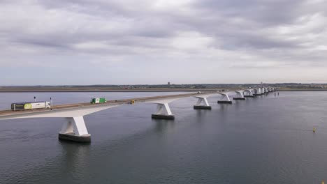 Multiple-Trucks-and-other-vehicles-driving-across-the-7km-long-Zeeland-bridge-in-the-south-west-region-of-the-Netherlands-on-an-overcast-morning