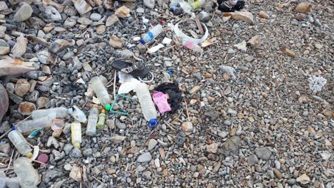 Schockierende-Haufen-Von-Plastikflaschen-Und-Müll,-Die-Bei-Flut-Vom-Ozean-Auf-Einer-Tropischen-Insel-Auf-Einen-Beliebten-Felsigen-Kiesstrand-Gekippt-Werden