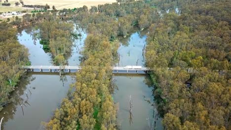 Drone-footage-of-a-truck-passing-across-a-Murray-Valley-Highway-bridge-over-the-Ovens-River-where-it-joins-the-Murray-River-near-Bundalong,-Victoria,-Australia