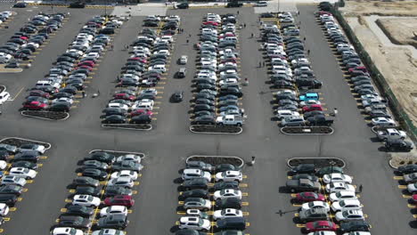 Timelapse-drone-footage-of-parking-lot,-with-people-and-cars-moving-around,-static-aerial