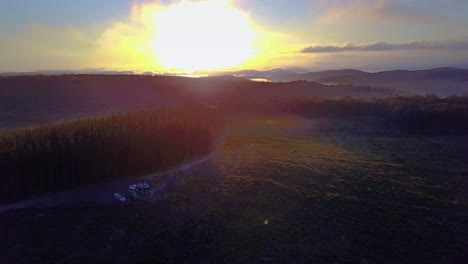 Drone-footage-of-sunrise-over-a-forest-covered-in-patches-of-fog