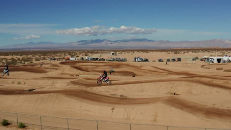 Two-motocross-racers-jumping-over-ramp-in-Mojave-Desert-landscape-track,-Aerial