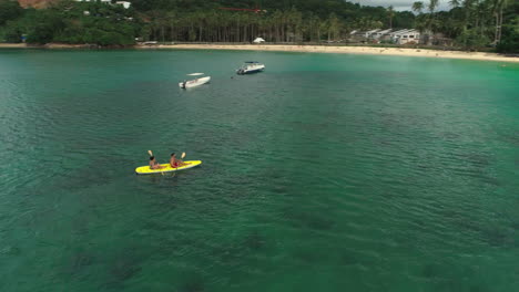 Aerial-orbit-of-a-young-couple-kayaking-in-El-Nido,-Philippines