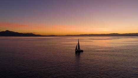 Flying-low-passing-next-to-sailboat-on-Lake-Léman-with-beautiful-sunset-colors-In-front-of-Lutry,-Lavaux---Switzerland