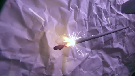 Close-Up-of-Fireworks-Light-Sparkler-Stick-and-a-Scratched-Paper-Background