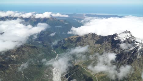 Luftaufnahme-Vom-Flugzeug-Rundflug-über-West-Coast-Fox-Glacier-Aoraki-Mount-Cook,-Nationalpark-Mit-Wolken,-Schneebedeckten-Rocky-Mountains-Und-Ozean-Im-Hintergrund