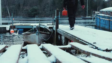 Walking-down-pier-with-petrol-for-boat-in-snow