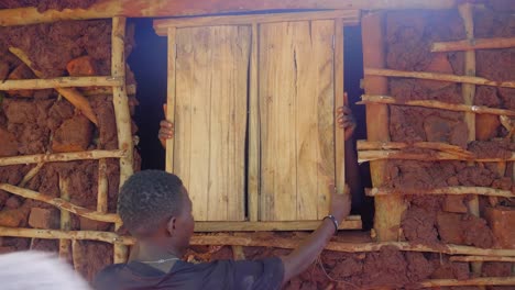 Africans-installing-a-wooden-window-into-a-traditional-style-mud-house-in-a-rural-African-village