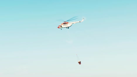 Helicopter-flying-off-after-filling-water-bucket-to-drop-on-forest-fire