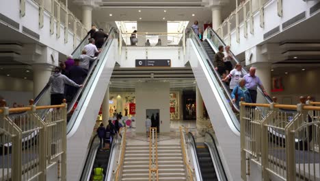 Travelling-down-an-esculator-in-the-Intu-Potteries-shopping-centre-in-the-city-centre,-Customers,-people-shopping-in-the-mall